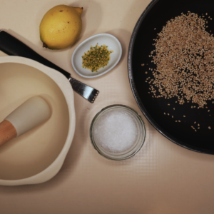 Les ingrédients pour préparer un gomasio au mélilot, avec du sel, des graines de sésame, du citron et du mélilot.