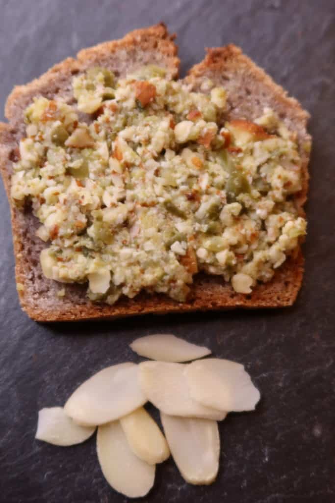 Tartinade végétale à base d'amandes et d'olives vertes, sur une tranche de pain sans gluten, de l'Ermite