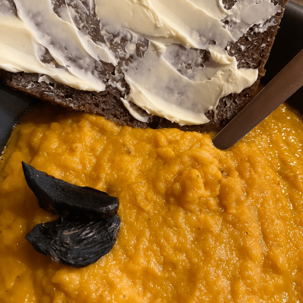 Une soupe de carotte, agrémentée d'ail noir et d'une tartine de pumpernikel et beurre.