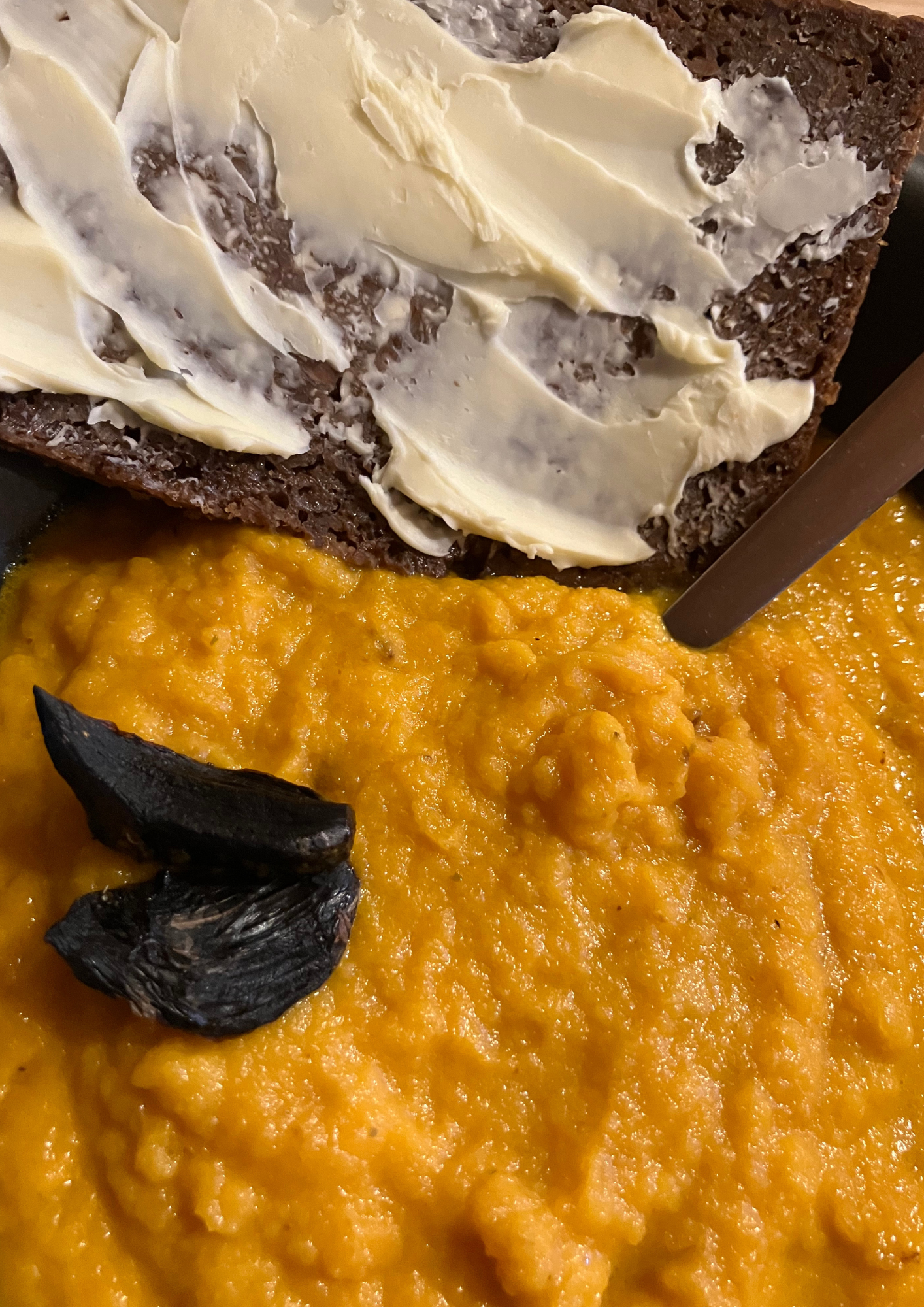 Une soupe de carotte, agrémentée d'ail noir et d'une tartine de pumpernikel et beurre.