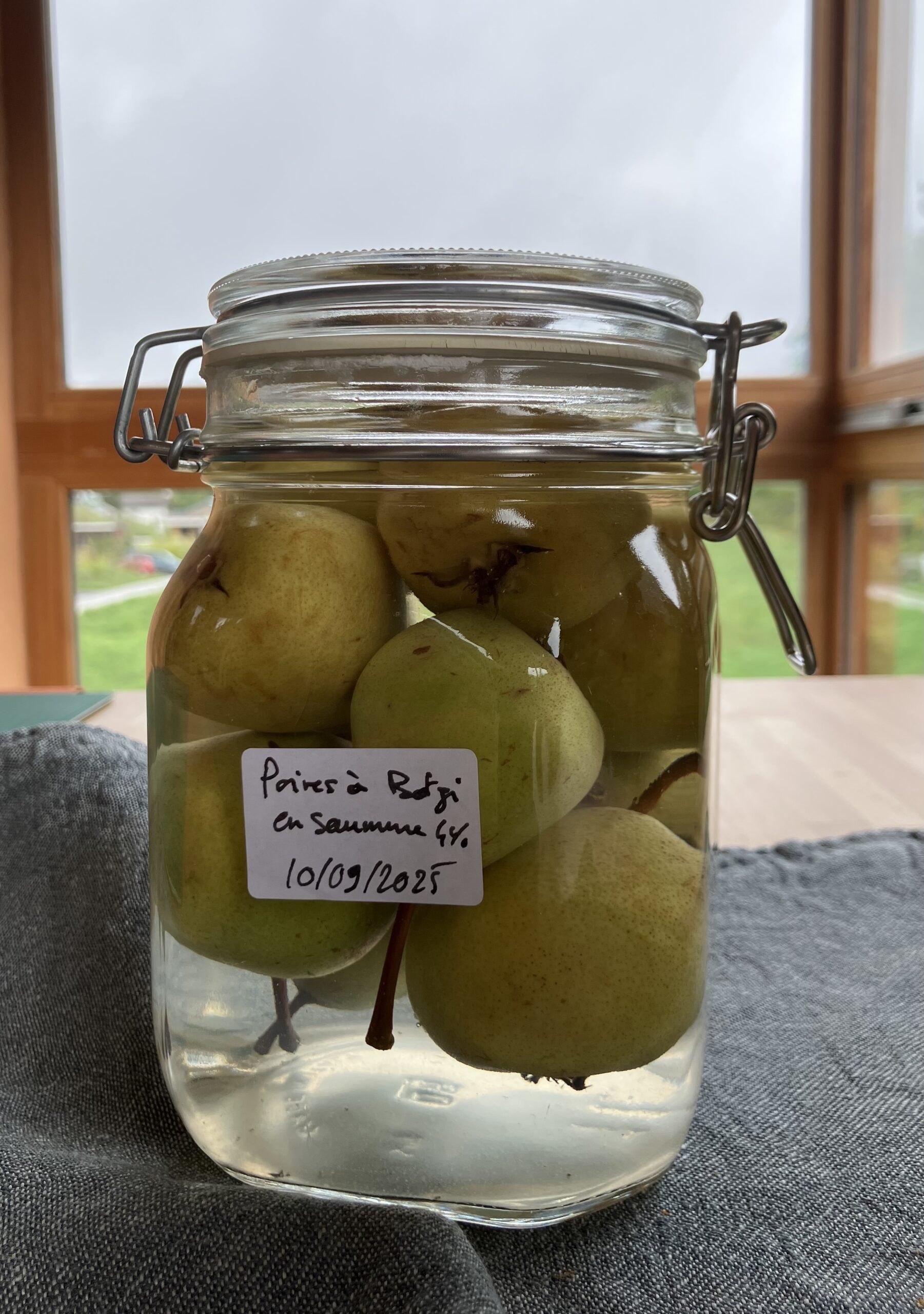 Des poires à Botzi en saumure, dans un bocal, posé sur une table.