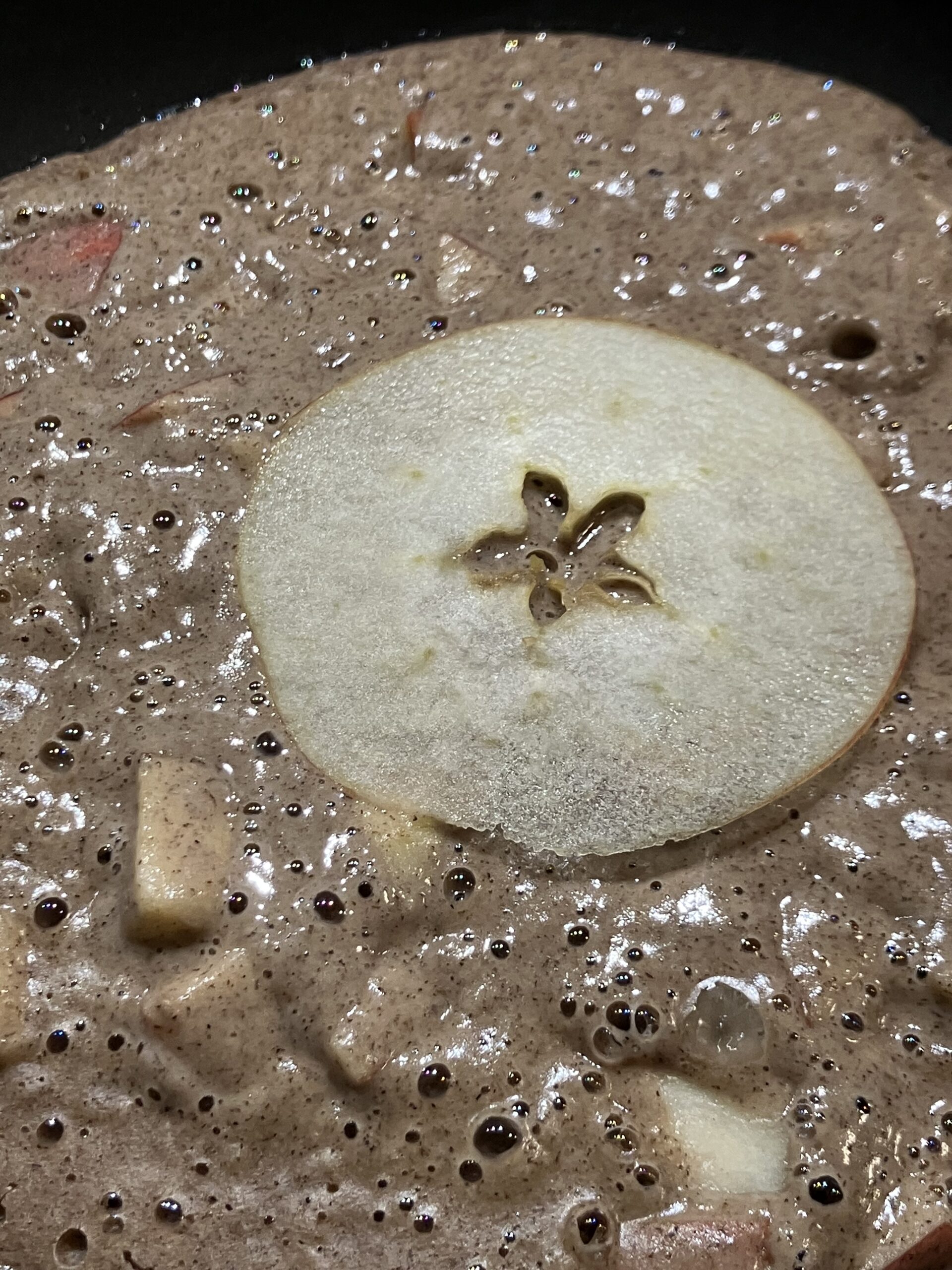 Une tranche de pomme, posée sur la première face de la galette sarrasin-châtaigne aux pommes.