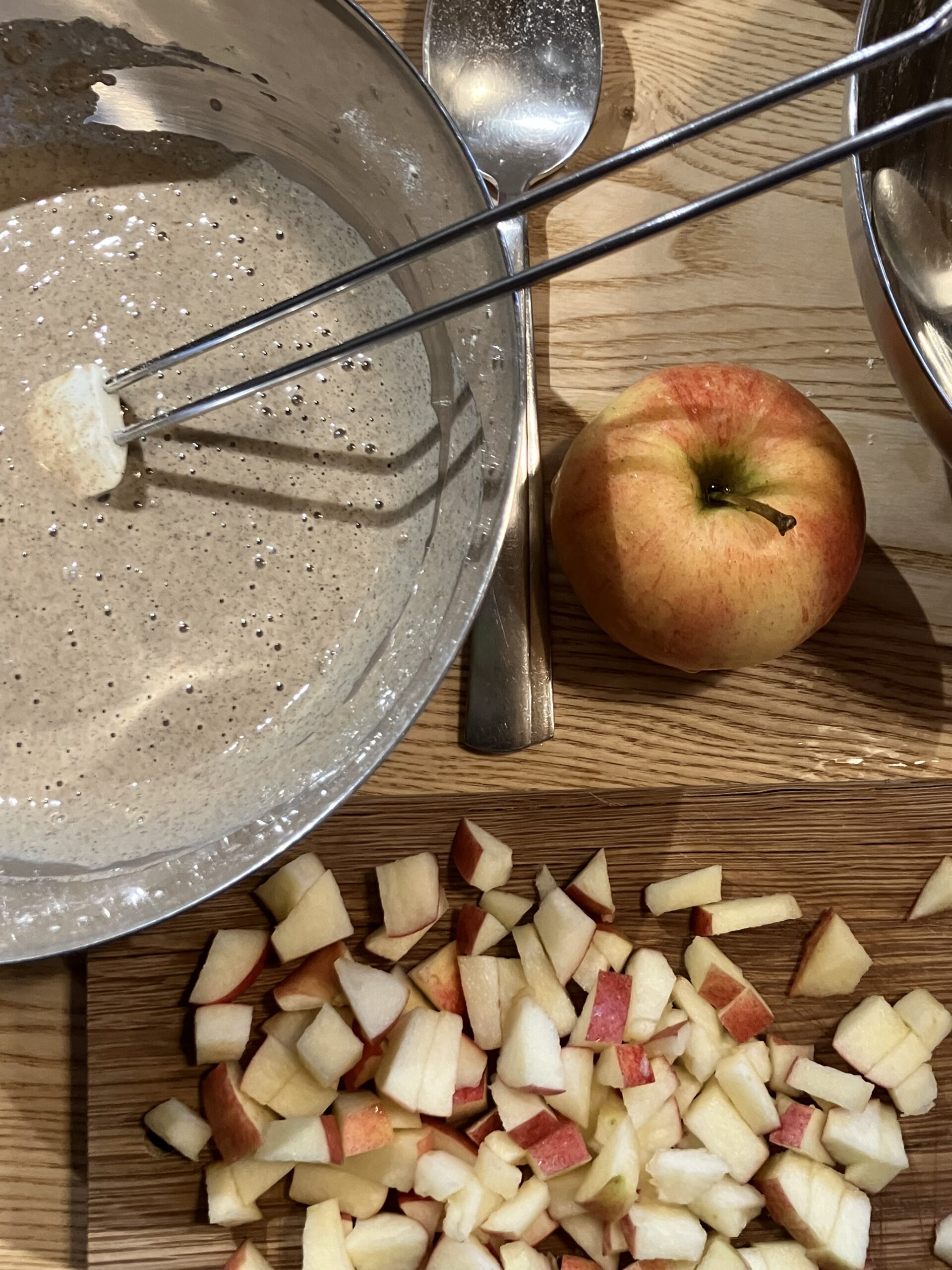 Un bol avec la préparation pour une galette sarrasin-châtaigne et une pomme rouge coupée en morceaux.