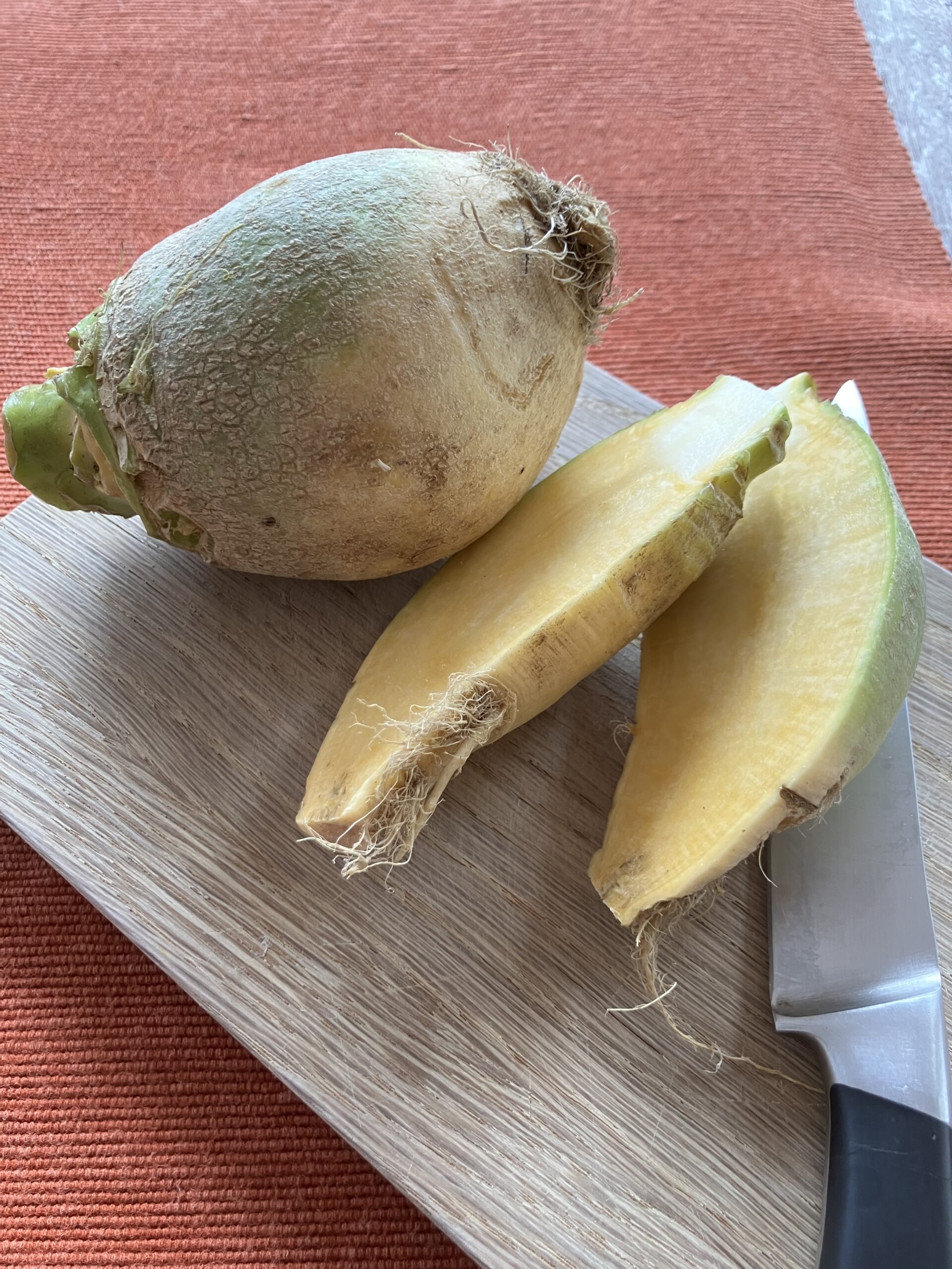 Un rutabaga entier, et une rutabaga coupé en deux, sur une planche à découpé.