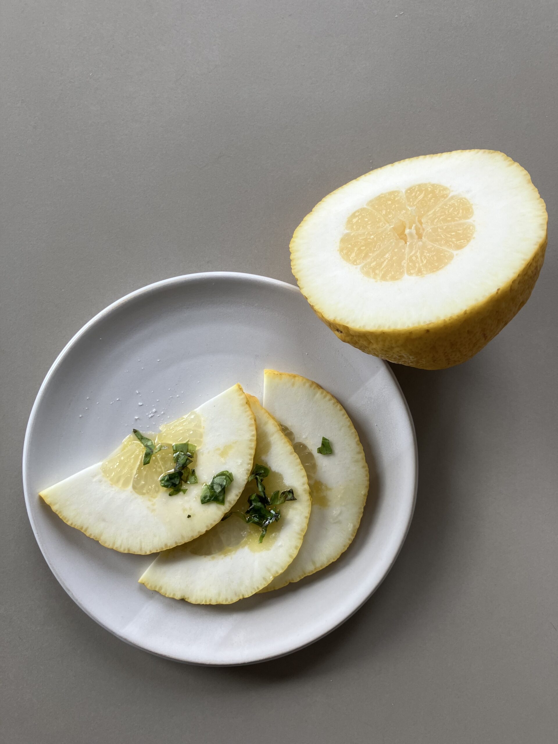 Un carpaccio de citron cédrat, posé sur une assiette blanche.